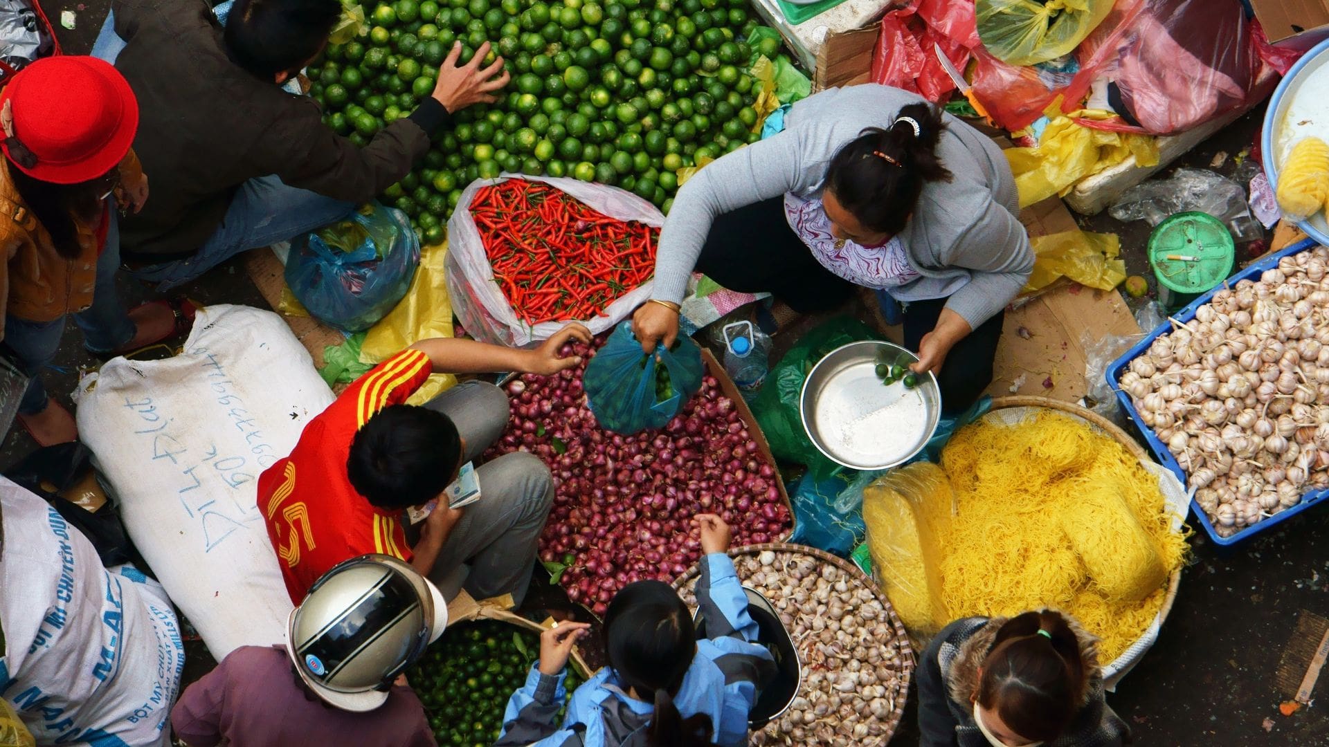 People at a colorful open market stall, seen from above.