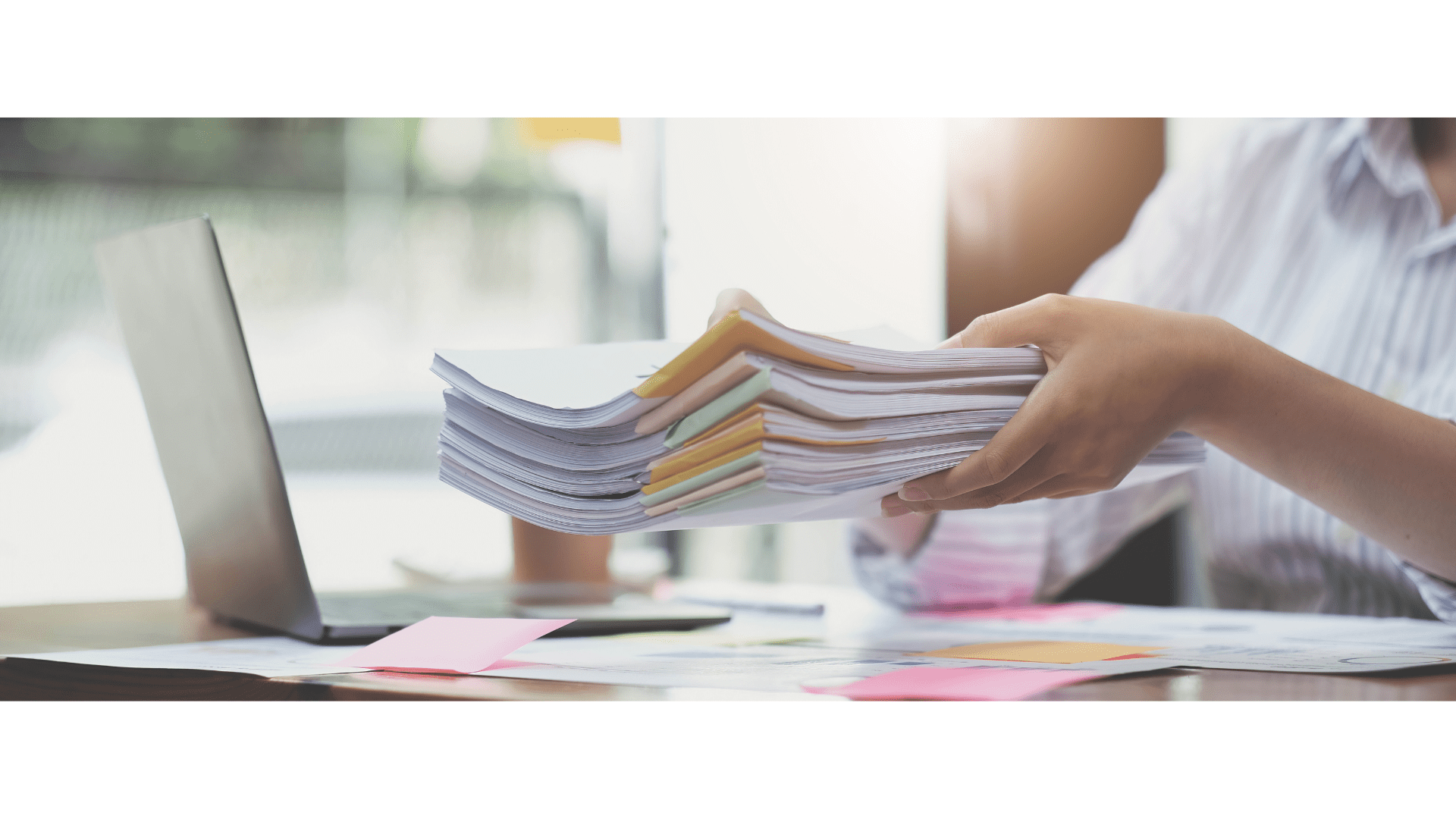 hands holding a stack of paper separated with binder clips and sticky notes